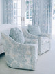 Bedroom featuring end-of-bed chairs upholstered in Peonies Pale Blue fabric, set in a calming pale blue and white interior. Design by Sara McCann, photography by Christina Cernik.